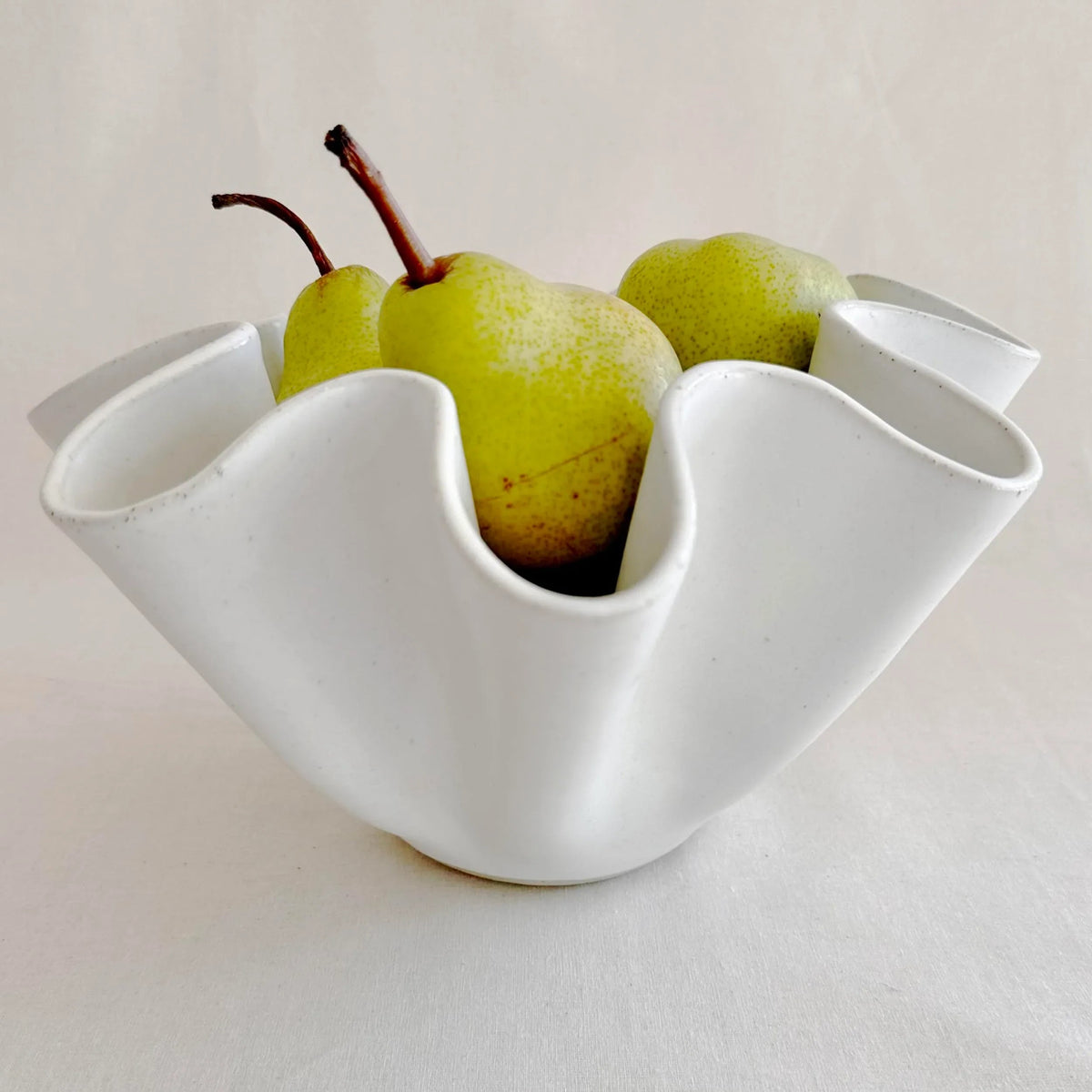 Pair of large white high sided wave bowls styled together on a table