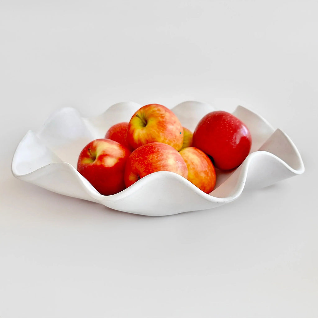 Large white wave bowl styled as a serving bowl on a dining table