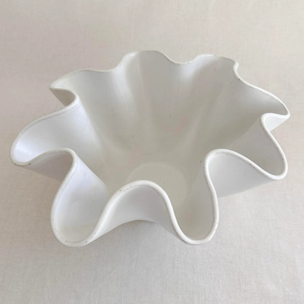 Large white high sided wave bowl shown on a sideboard in a styled interior